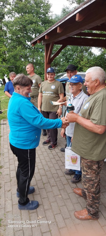 Zawody wędkarskie Wręczenie nagród za udział w zawodach. uczestniczka odbiera puchar.