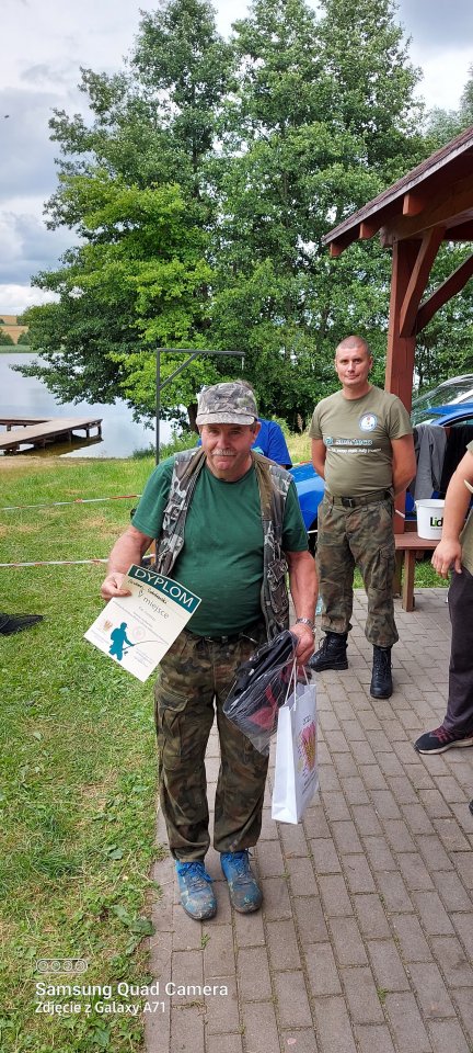 Zawody wędkarskie Uczestnik zawodów z nagrodami w ręku.