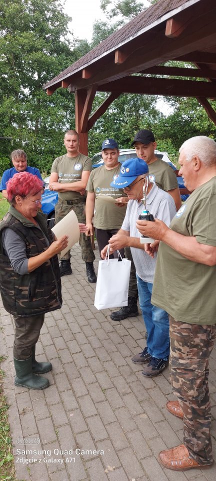 Zawody wędkarskie zawodniczka odbiera nagrodę za udział w zawodach wędkarskich.