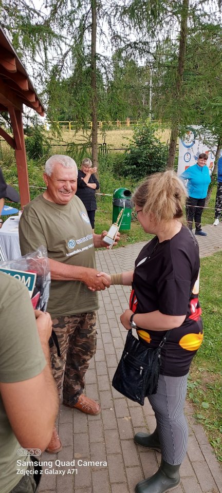 Zawody wędkarskie zawodniczka odbiera puchar za udział w zawodach wędkarskich.