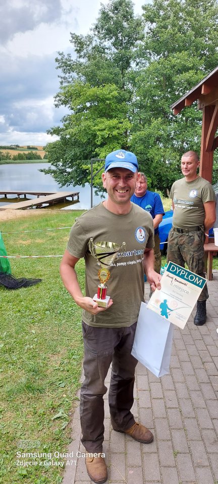 Zawody wędkarskie uśmiechnięty zawodnik z nagrodą w ręku