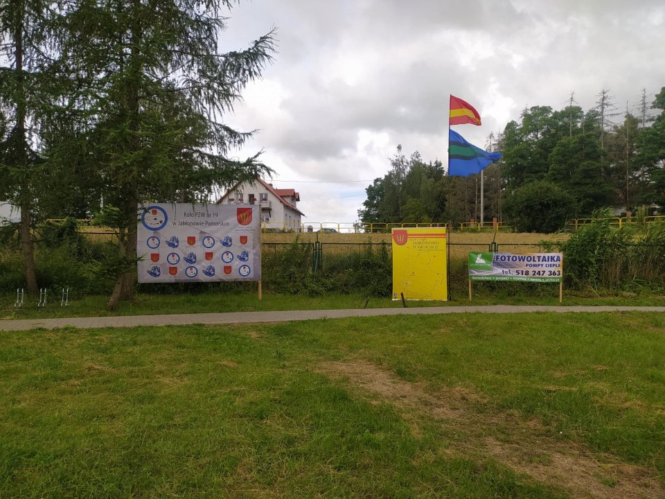 Zawody wędkarskie Plaża nad jeziorem dużym w Nowej Wsi, w tle ścianki reklamowe i flagi.