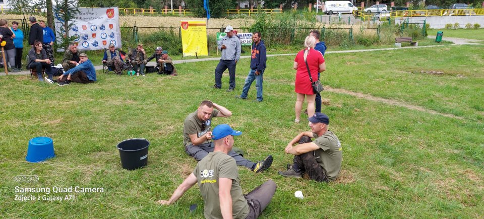 Zawody wędkarskie grupa wędkarzy siedzi na terenie plaży w Nowej Wsi.