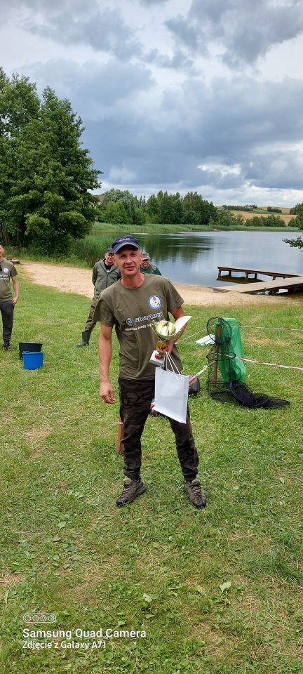 Zawody wędkarskie Wędkarz z pucharem i nagrodą w ręku.